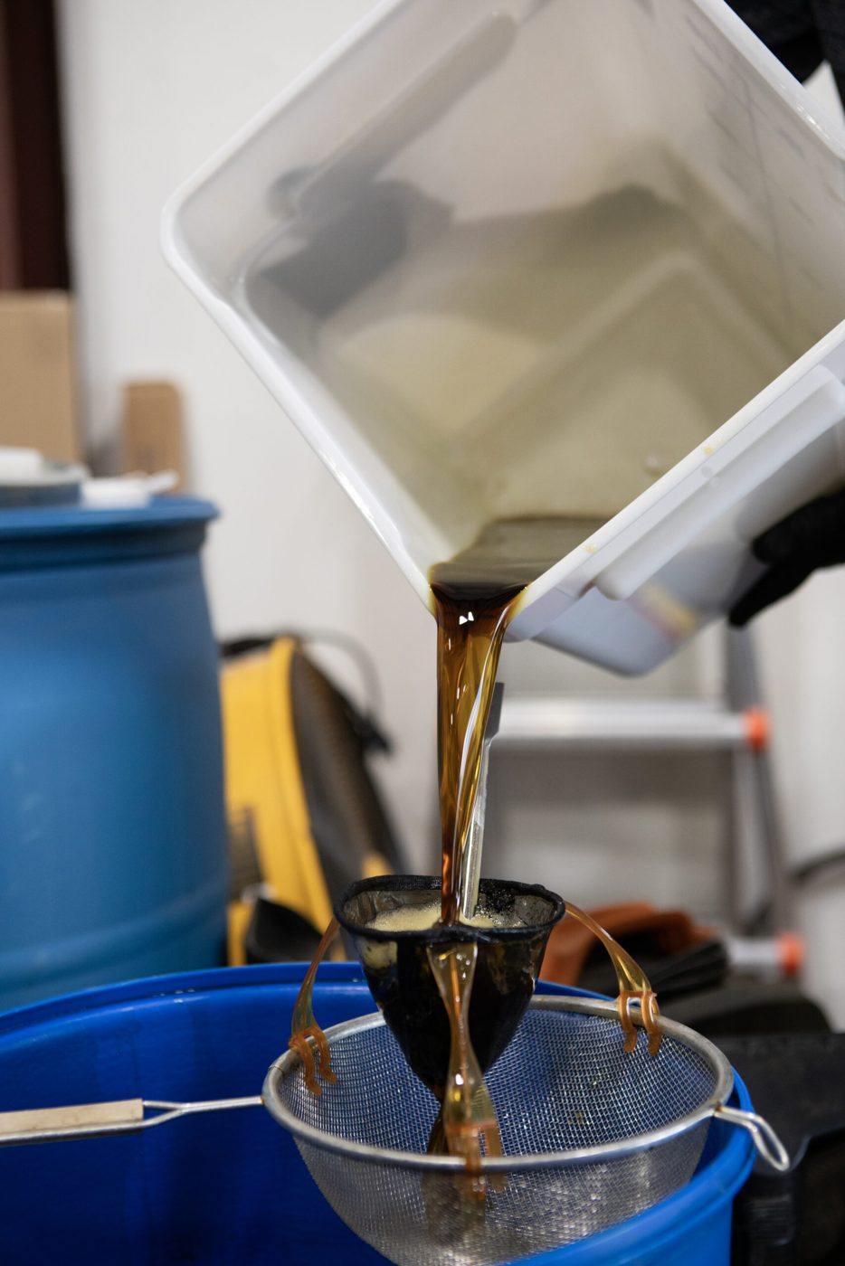 Pouring dark mushroom extract through a filter