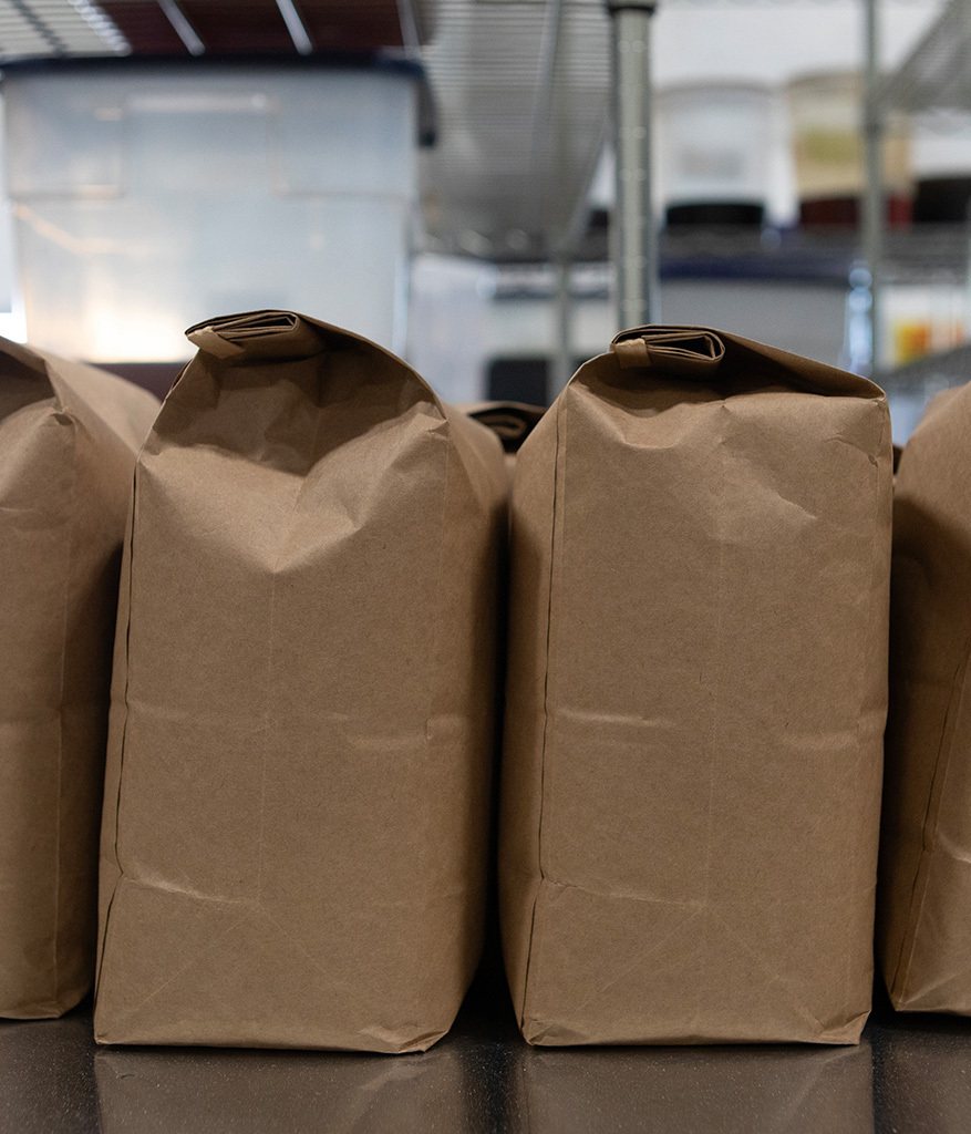 Sealed paper bags lined up on a stainless table