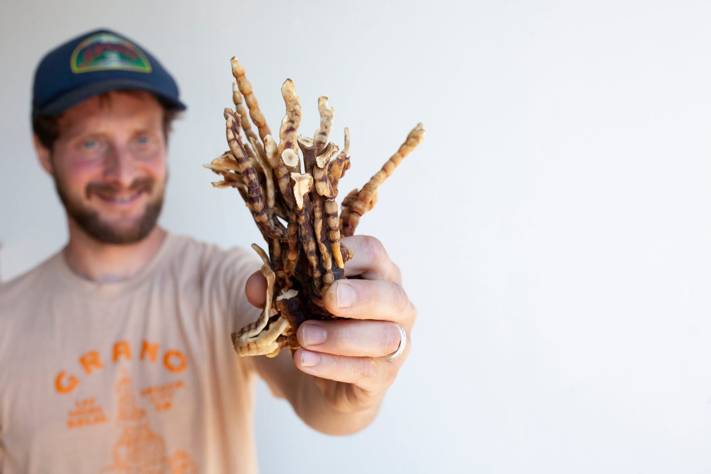 Team member holding a bundle of dried mushrooms